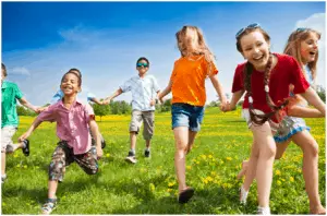 Children running in grass field with flowers