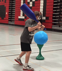Student batting ball on tee